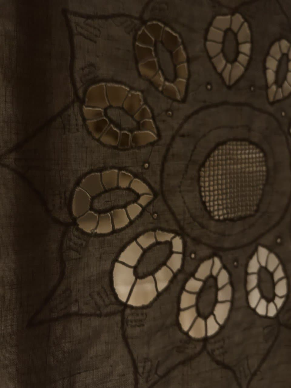 Cutwork embroidery with a flower pattern, lit from behind