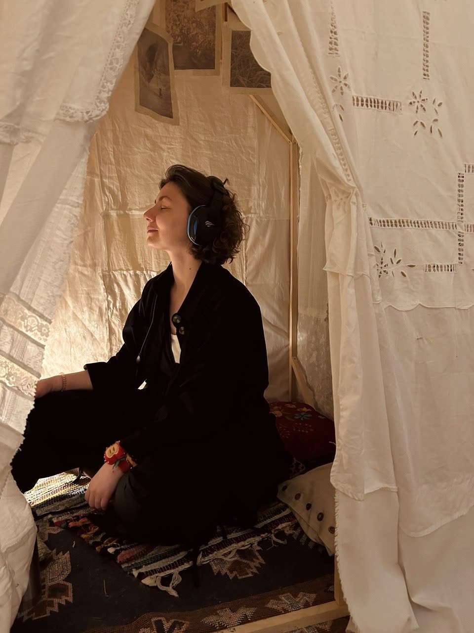 A visitor in headphones sitting inside the textile house with eyes closed